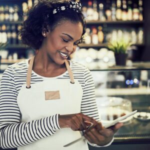 Young African entrepeneur standing in her cafe using a tablet